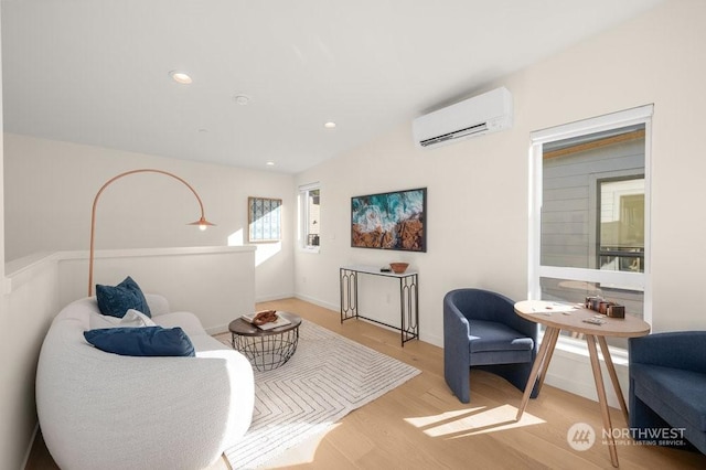 sitting room featuring a wall mounted AC and light wood-type flooring