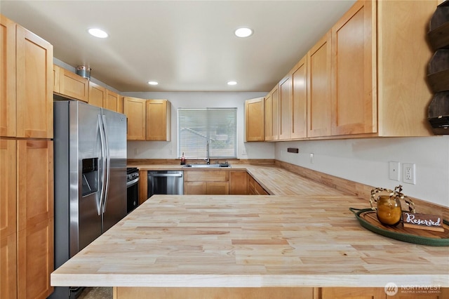 kitchen featuring a sink, light brown cabinetry, butcher block countertops, dishwasher, and stainless steel fridge