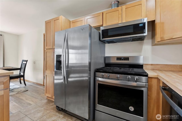 kitchen with light brown cabinetry, butcher block countertops, appliances with stainless steel finishes, and light tile patterned flooring