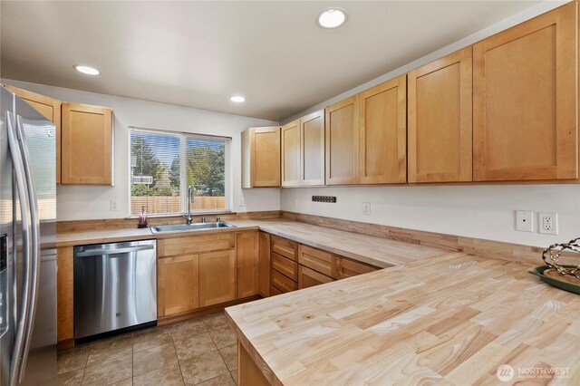 kitchen with a sink, recessed lighting, wood counters, and stainless steel appliances