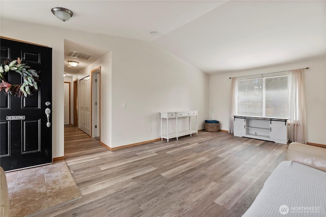 foyer entrance with vaulted ceiling, wood finished floors, visible vents, and baseboards