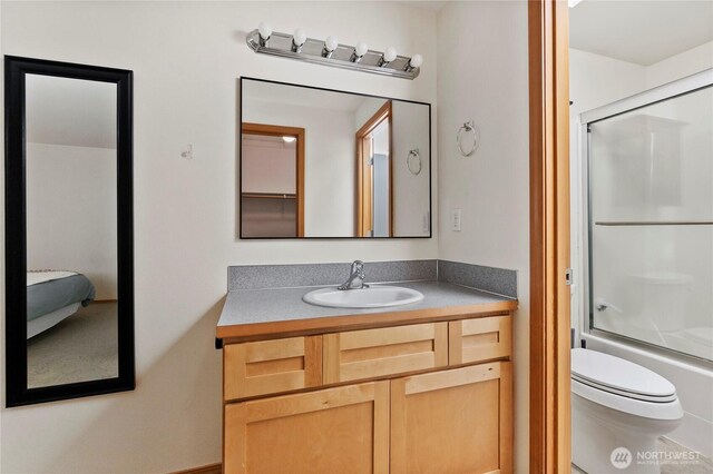 full bathroom featuring toilet, vanity, and shower / bath combination with glass door