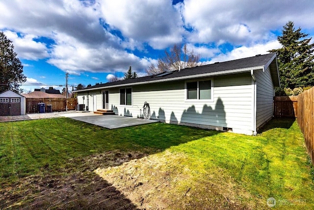 back of property with a storage unit, a lawn, a fenced backyard, an outdoor structure, and a patio area