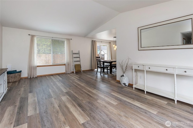 interior space featuring wood finished floors, baseboards, and vaulted ceiling