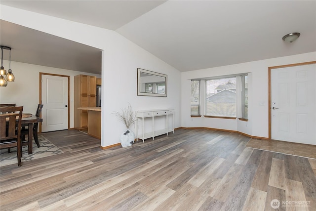 entryway featuring baseboards, light wood-style floors, and vaulted ceiling