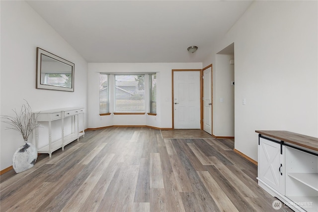 entrance foyer featuring light wood finished floors, lofted ceiling, and baseboards