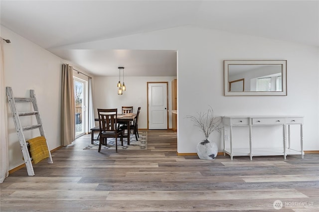 dining space featuring lofted ceiling, wood finished floors, and baseboards