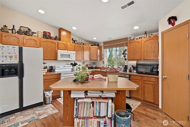 220 California St, Pe Ell, WA 98572 - kitchen with white appliances, light wood-type flooring, light countertops, a kitchen island, and a sink