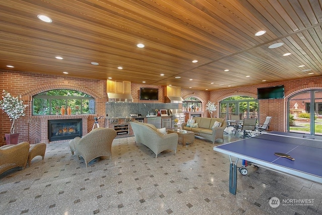 rec room with brick wall, light carpet, and wooden ceiling