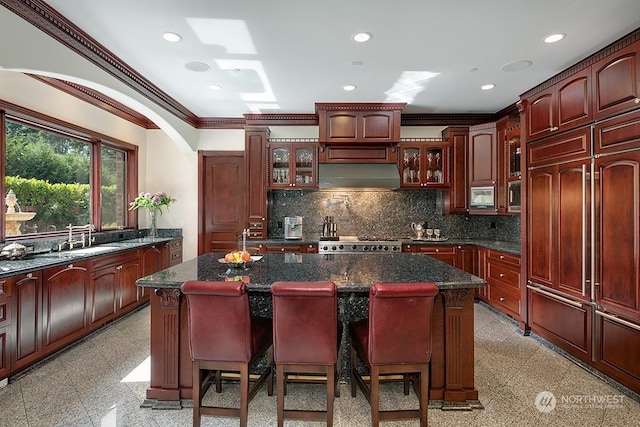 kitchen featuring a kitchen bar, sink, crown molding, range, and a center island with sink