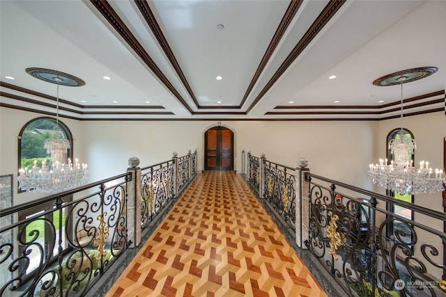 corridor featuring an inviting chandelier, crown molding, a raised ceiling, and light parquet flooring