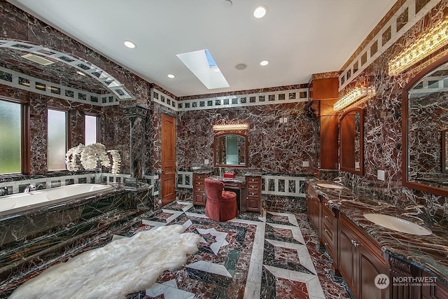 bathroom featuring tiled tub, vanity, and a skylight