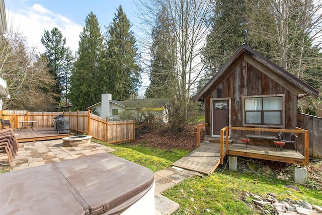 view of yard with a deck, a patio area, a fire pit, and fence