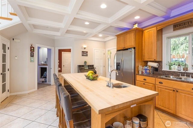 kitchen with an island with sink, a sink, wood counters, and stainless steel fridge with ice dispenser