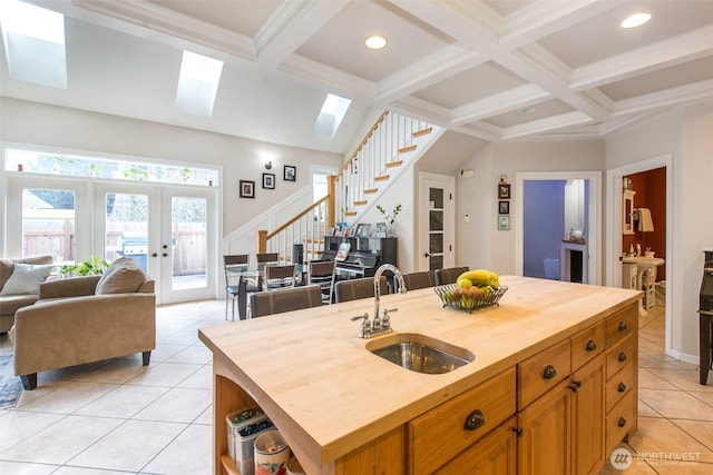 kitchen featuring butcher block countertops, french doors, a sink, and beamed ceiling
