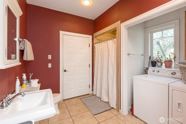 bathroom with curtained shower, toilet, a sink, separate washer and dryer, and tile patterned flooring