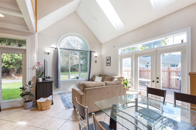 dining room featuring a skylight, french doors, light tile patterned floors, high vaulted ceiling, and baseboards
