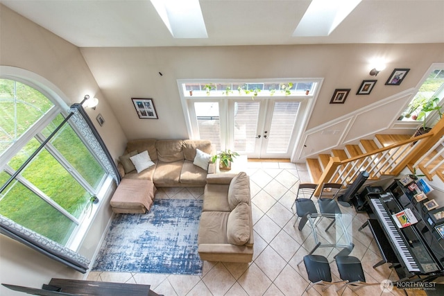 living area featuring a skylight, french doors, tile patterned flooring, and stairs
