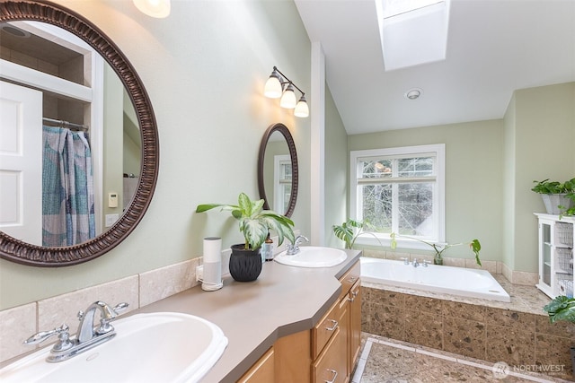 full bathroom featuring a garden tub, double vanity, a skylight, and a sink