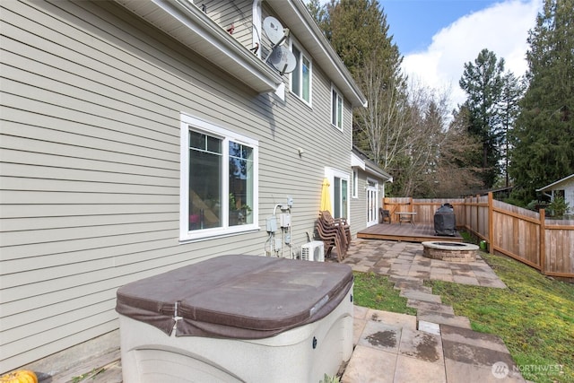 view of patio with an outdoor fire pit, fence, a hot tub, and a wooden deck