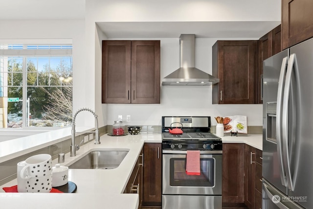 kitchen featuring wall chimney exhaust hood, appliances with stainless steel finishes, sink, and dark brown cabinets