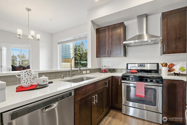 kitchen with stainless steel appliances, a wealth of natural light, sink, and wall chimney range hood