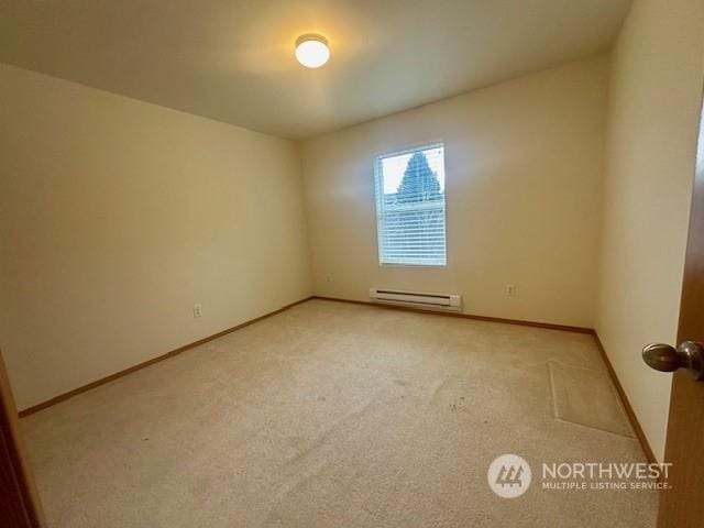 carpeted empty room with a baseboard heating unit