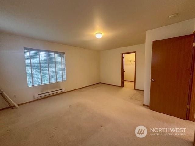 empty room featuring a baseboard radiator and light colored carpet