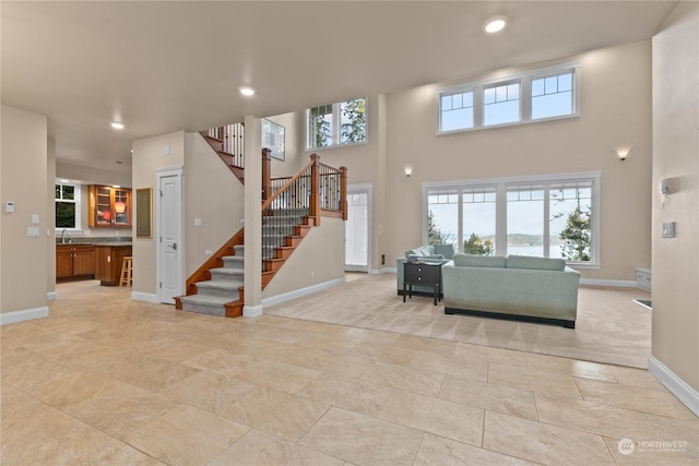 living room featuring a towering ceiling, plenty of natural light, and sink