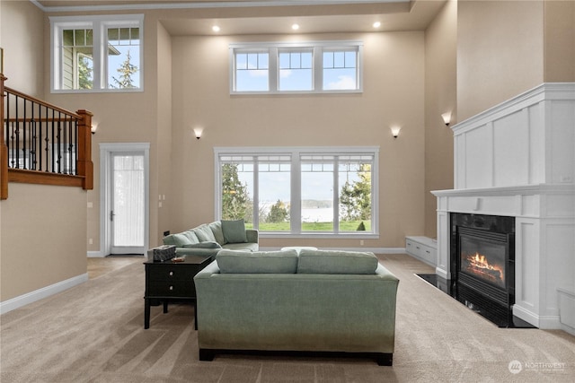 living room featuring a towering ceiling, a fireplace, and light colored carpet