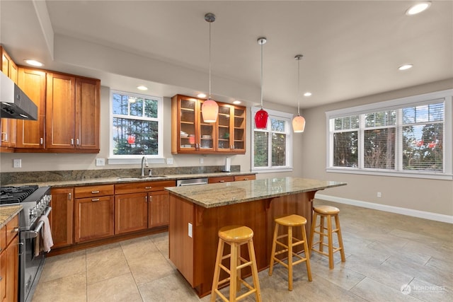 kitchen with light stone counters, decorative light fixtures, a kitchen breakfast bar, a kitchen island, and stainless steel appliances