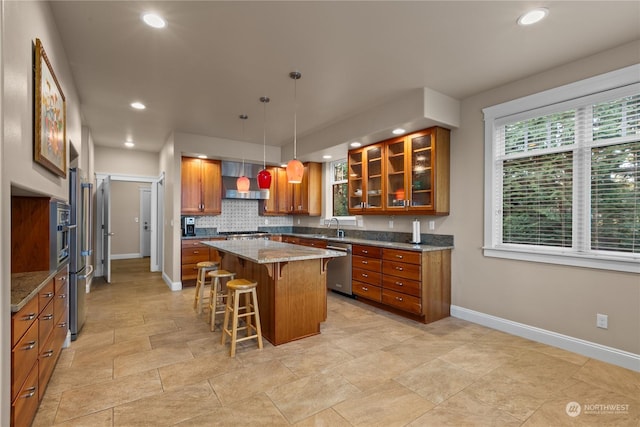 kitchen featuring a kitchen island, a breakfast bar, pendant lighting, dishwasher, and light stone countertops