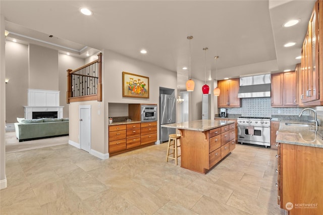 kitchen featuring wall chimney range hood, sink, a breakfast bar area, a center island, and premium appliances