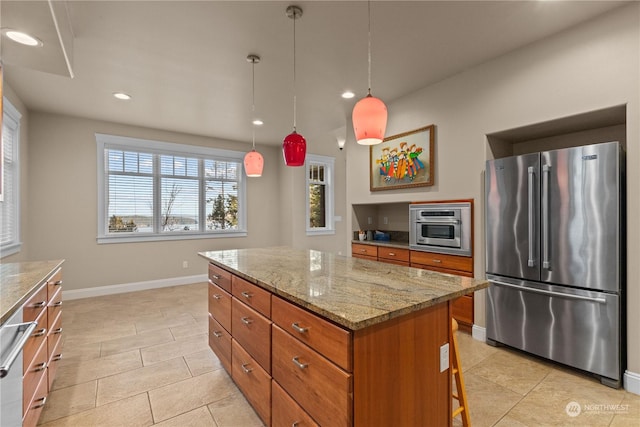 kitchen featuring hanging light fixtures, appliances with stainless steel finishes, a center island, and light stone counters