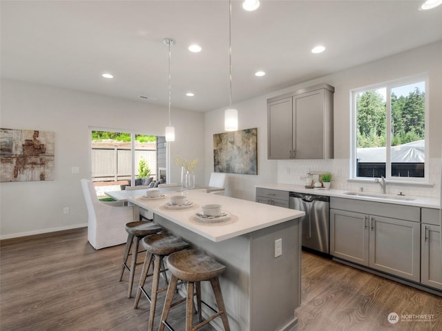 kitchen with sink, a center island, hanging light fixtures, gray cabinets, and dishwasher