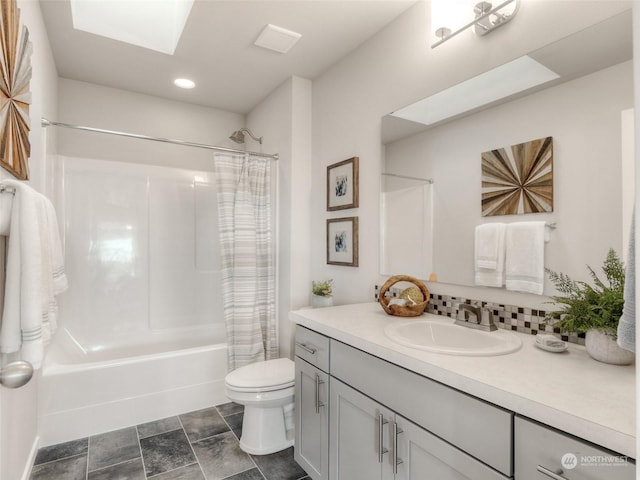 full bathroom with shower / bath combination with curtain, vanity, toilet, and a skylight