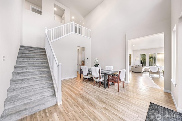 dining area with a high ceiling and light hardwood / wood-style flooring