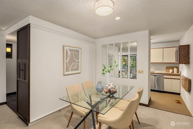 dining area featuring light colored carpet and a textured ceiling