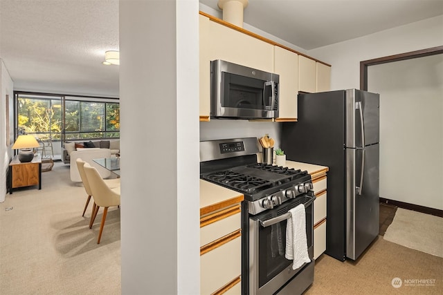 kitchen with white cabinetry, light carpet, stainless steel appliances, and a textured ceiling