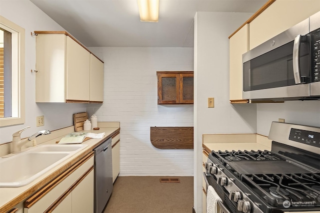 kitchen featuring appliances with stainless steel finishes, sink, and cream cabinetry