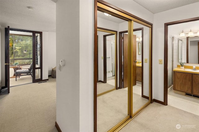 hall with sink, light carpet, a textured ceiling, and french doors