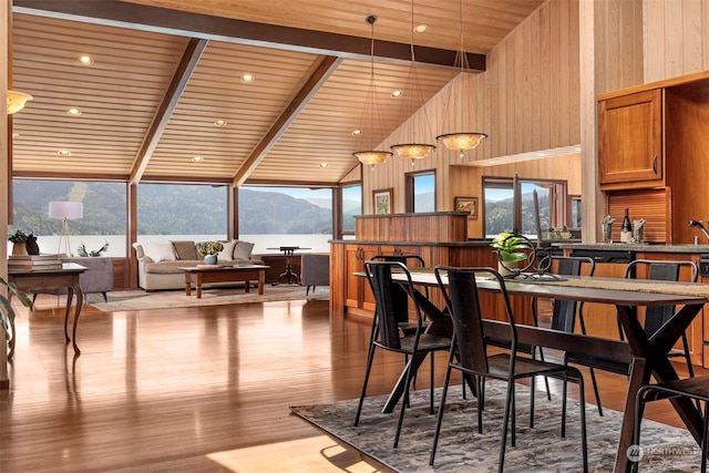 dining room featuring light hardwood / wood-style flooring, wooden walls, high vaulted ceiling, a mountain view, and wooden ceiling