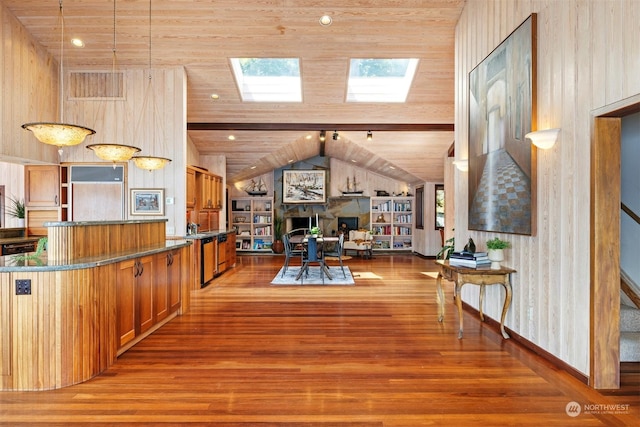 interior space with lofted ceiling with skylight, wood ceiling, dark stone countertops, hardwood / wood-style flooring, and pendant lighting