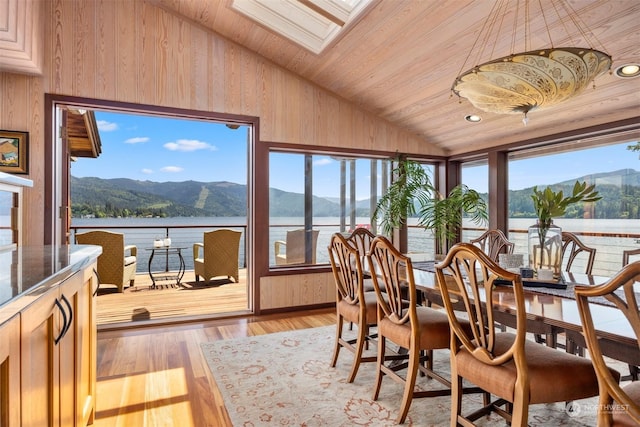 sunroom with a water and mountain view, lofted ceiling with skylight, a wealth of natural light, and wooden ceiling