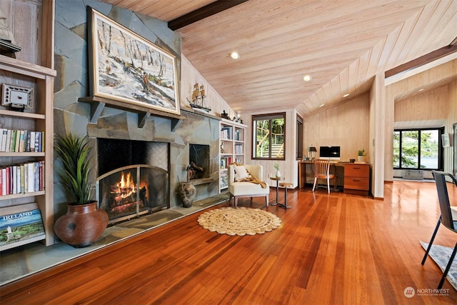 living area featuring hardwood / wood-style flooring, vaulted ceiling, a healthy amount of sunlight, and a fireplace