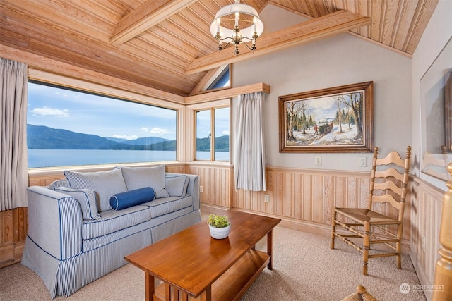 carpeted living room featuring vaulted ceiling with beams, a notable chandelier, a water and mountain view, wooden ceiling, and wood walls