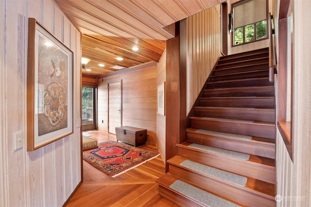 staircase with hardwood / wood-style flooring, a healthy amount of sunlight, wooden walls, and wood ceiling