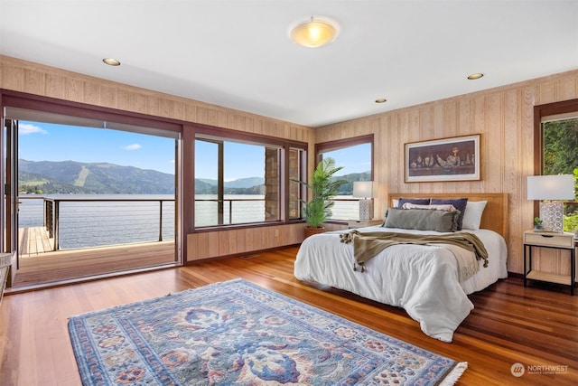 bedroom with hardwood / wood-style flooring, access to outside, and a water and mountain view