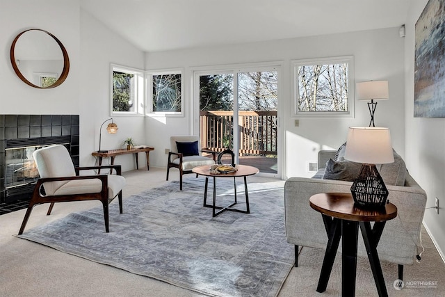 sitting room with lofted ceiling, a tile fireplace, and carpet