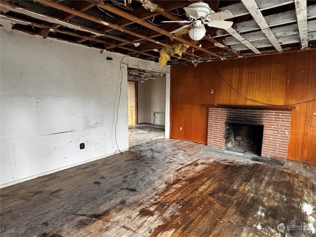 unfurnished living room with wood-type flooring, a brick fireplace, and wood walls